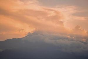 Beautiful view of Mount Etna covered with clouds and smoke during sunset photo