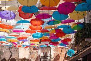 vista de ángulo bajo de sombrillas multicolores colgando en medio de edificios en un día soleado foto