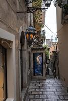 Illuminated lantern hanging outside old building in alley with sky in background photo