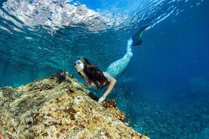 sirena nadando bajo el agua en el mar azul profundo foto