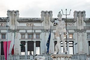 Birds perching on Neptune Statue fountain with historic building in background photo