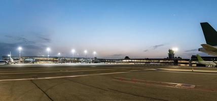 Panoramic view of airplanes on runway at illuminated international airport photo