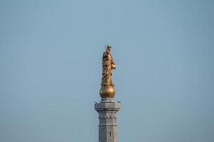 vista de ángulo bajo de la hermosa estatua de la madonna dorada con cielo azul en segundo plano foto