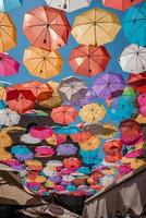 Low angle view of multi colored umbrellas hanging amidst buildings in summer photo