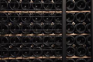 botellas de vino dispuestas en una estantería para el envejecimiento en la bodega foto