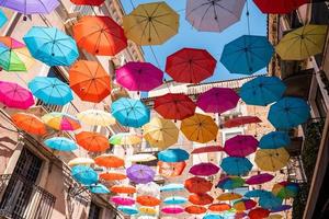 vista de ángulo bajo de hermosos paraguas coloridos que cuelgan en medio de los edificios de la ciudad foto