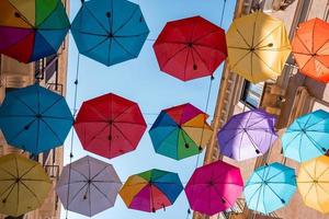 vista de coloridas sombrillas decoradas en medio de edificios con el cielo de fondo foto