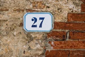 número 27 sobre fondo de pared de piedra y ladrillo foto