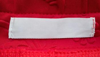 blank white clothing label on red fabric texture background photo