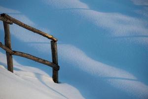 una valla de madera en el fondo de la nieve foto