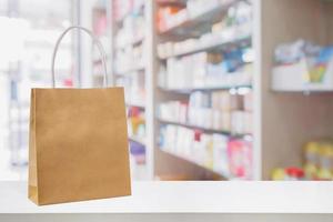 Paper bag on Pharmacy drugstore counter table with medicine and healthcare product on shelves blur background photo