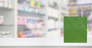 Paper bag on Pharmacy drugstore counter table with medicine and healthcare product on shelves blur background photo