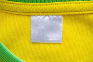 etiqueta de ropa textil blanca en blanco sobre textura de jersey de tela de ropa deportiva amarilla foto