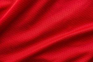 camiseta de fútbol de ropa deportiva de tela roja con fondo de textura de malla de aire foto