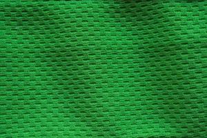camiseta de fútbol de ropa deportiva de tela verde con fondo de textura de malla de aire foto