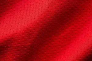 Red fabric sport clothing football jersey with air mesh texture background photo