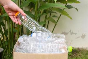 Hand hold and put plastic bottles in to brown recycle garbage box photo