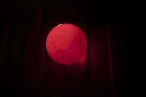 Red ball in dark. Signal lamp on fence. photo