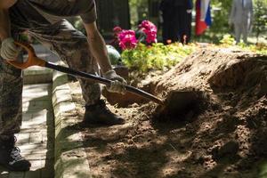 Man digs grave. Guy with shovel digs ground. Funeral details. photo