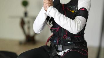 Young woman wearing electrodes suit on physical therapy video