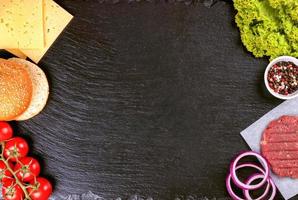 The raw ingredients for the homemade burger on black slate background. Top view. photo