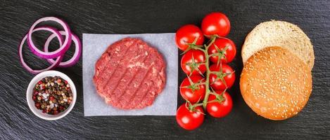 The raw ingredients for the homemade burger on black slate background. Top view. photo