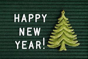 Happy new year , text on green felt letter board with white letters and green toy fir photo