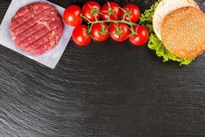 The raw ingredients for the homemade burger on black slate background. Top view. photo