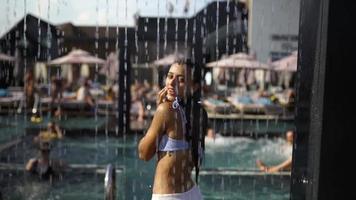 mujer joven en traje de baño duchándose en el parque acuático