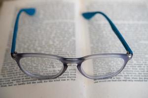 light blue reading glasses isolated on a book photo