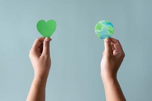 Hands holding earth and green heart shape. Concept of protecting the world from global warming with eco-heart in mind. photo