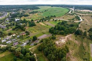aerial panoramic view of green village with houses, barns and gravel road in forest photo