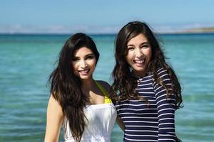 Two girls smiling in love on the beach photo