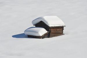 una cabaña de madera en el fondo de la nieve invernal foto