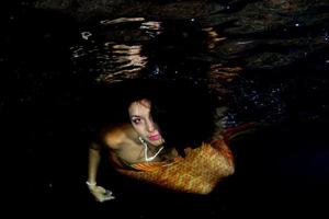 Mermaid swimming underwater in the deep blue sea photo