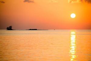 puesta de sol dorada en la pequeña isla de maldivas foto
