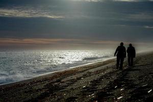 man and woman silhouette on beach at sunrise photo