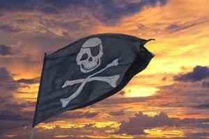 waving pirate flag jolly roger on sky background photo