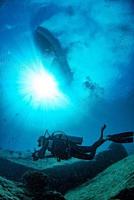 boat ship from underwater blue ocean with sun rays and scuba diver photo