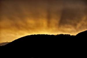 una puesta de sol naranja fuego sobre una montaña foto