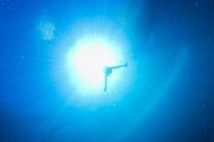 backlight diver underwater coming to the deep ocean photo