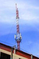torre de comunicación con antenas en la parte superior del edificio y fondo de cielo azul brillante. foto