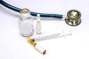 vial, 3 ml. ampolla de droga y jeringa de plástico con estetoscopio médico sobre fondo blanco. foto