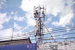 torre de comunicación con antenas en la parte superior del edificio y cielo azul brillante con fondo de nubes grandes. foto
