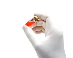 la mano de la enfermera en un guante blanco de látex médico recogió un vial de medicamento aislado sobre fondo blanco. foto