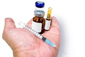 3 ml. ampollas y viales de fármaco con jeringa de plástico colocados en una aguja médica a mano aislada sobre fondo blanco. foto