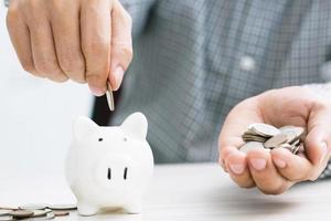 close up hand business man accounting calculate calculator expenses with savings money coins stacked row with hand putting coins Coins drop into piggy bank. concept Write Finance accounting. photo