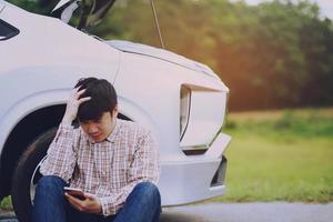close up businessman hand using a mobile smart phone call a car mechanic ask for help assistance because car broken roadside. people journey friends sit wait beside broken car photo