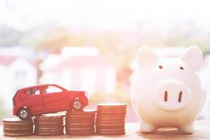Little white and red two car over a lot of money stacked coins. for  bank loans costs finance. insurance, buying car finance concept. buy and pay by installments down payment a car. photo