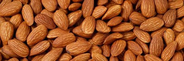 Background of big raw peeled almonds situated arbitrarily photo